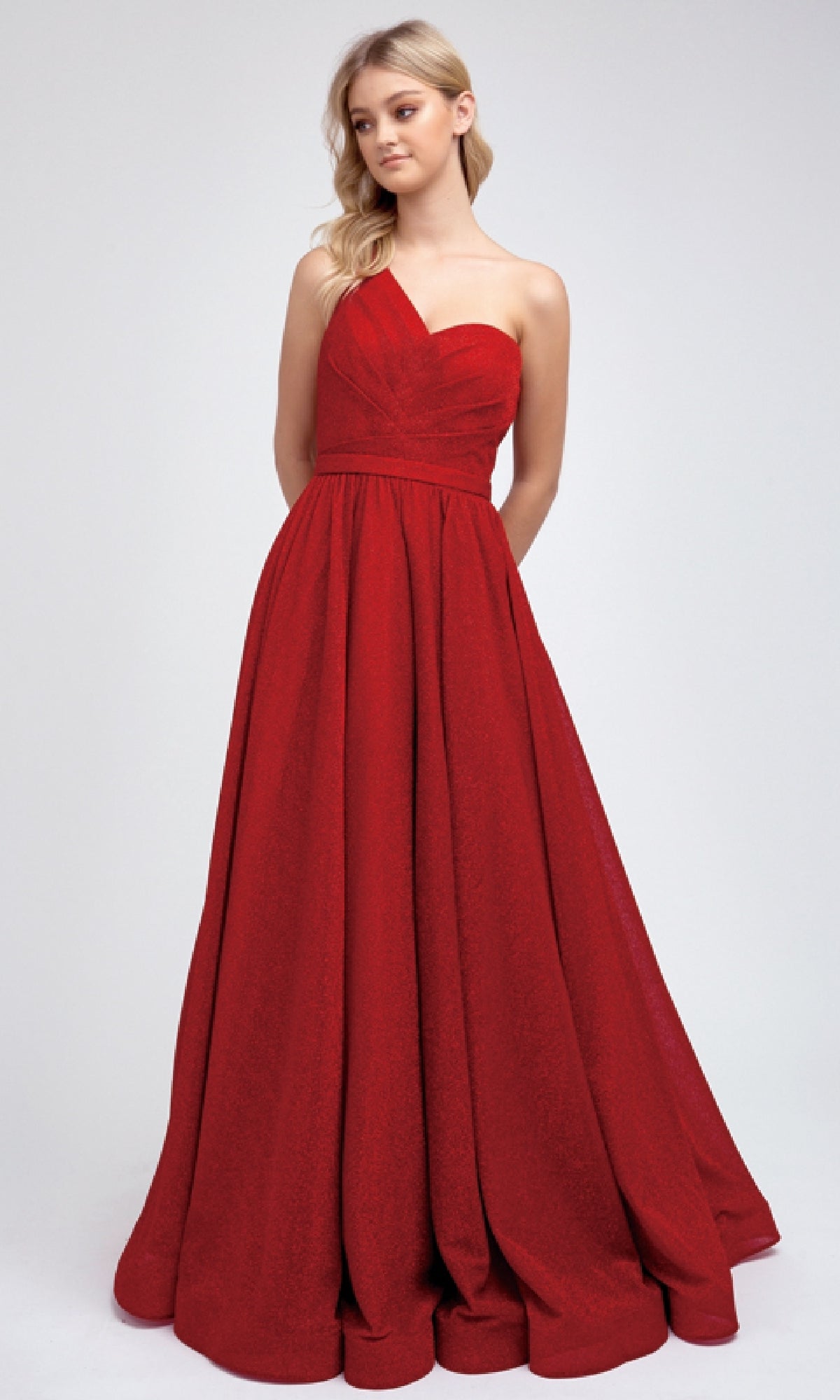 A woman wears the Juliet 205, a floor-length red prom dress with a one-shoulder fitted bodice and full A-line skirt—perfect for making an entrance at any event.